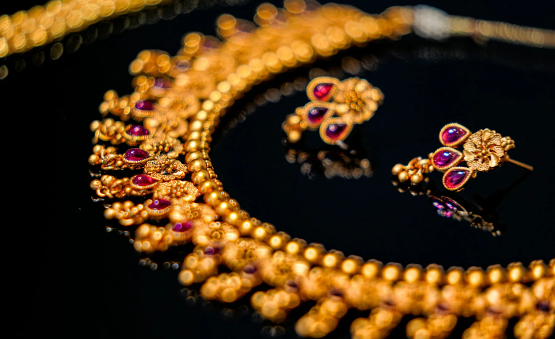 A gold necklace and earrings on dark velvet